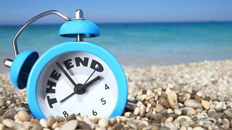 Una sveglia su una spiaggia: simbolo della fine delle vacanze
