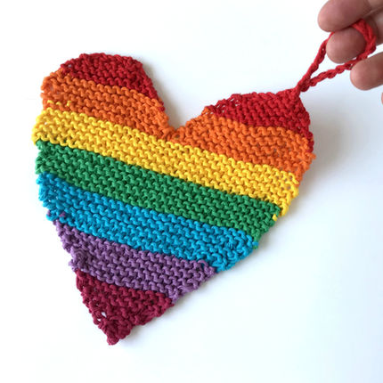 Rainbow striped knit cotton washcloth with hand for scale