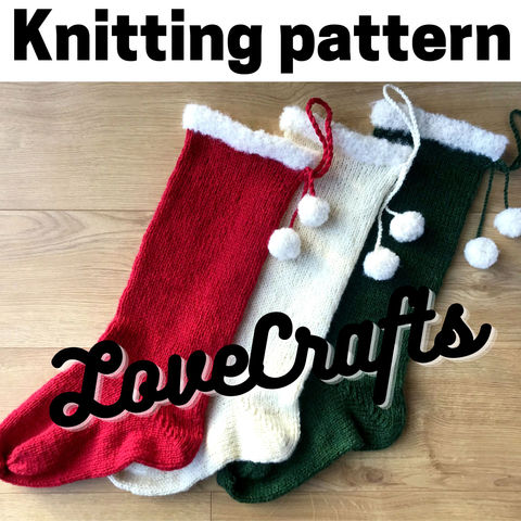 3 knit Christmas stockings (1 red, 1 cream, 1 green) with cream fluffy cuffs and pompoms, lying on a wooden surface