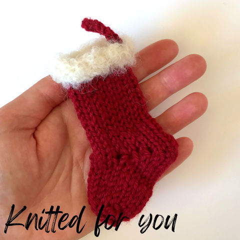 Tiny red knit stocking with fluffy cuff, held in a hand