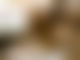 A high-angle shot of marketing strategist Katina Ndlovu in a mustard gold suit, sitting on the floor amidst a sea of brainstorming notes and cards. She smiles upward, holding a card that represents finding the perfect business name. The scene conveys creativity and discovery