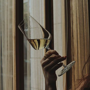 Woman gracefully holding a champagne glass, delicately tilting it to the side. Her poised gesture exudes elegance.
