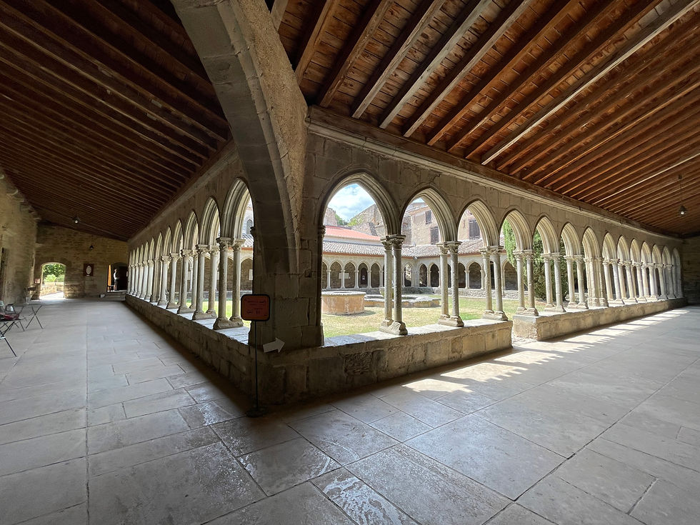 A tranquil photo of the cloister at Abbaye de Saint-Hilaire, featuring a serene courtyard surrounded by arches.