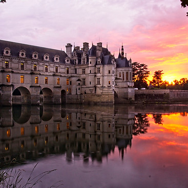 Sunset view of Chateau de Chenonceau reflecting gracefully on the tranquil river.