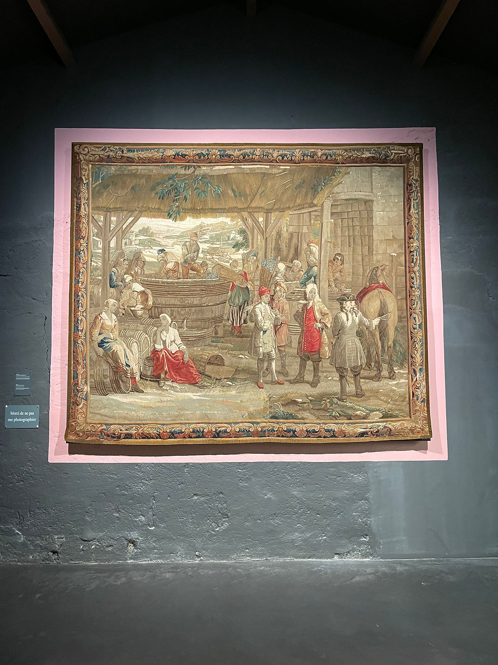 This exquisite 18th-century tapestry depicts a grape harvest scene with its distinctive hilly landscape and a man holding a tastevin in Burgundy.