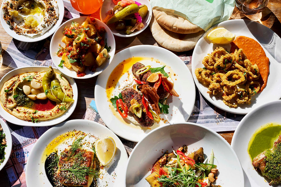 A vibrant spread of Mediterranean dishes includes hummus, fried calamari, and colorful salads on a wooden table, creating a lively mood.