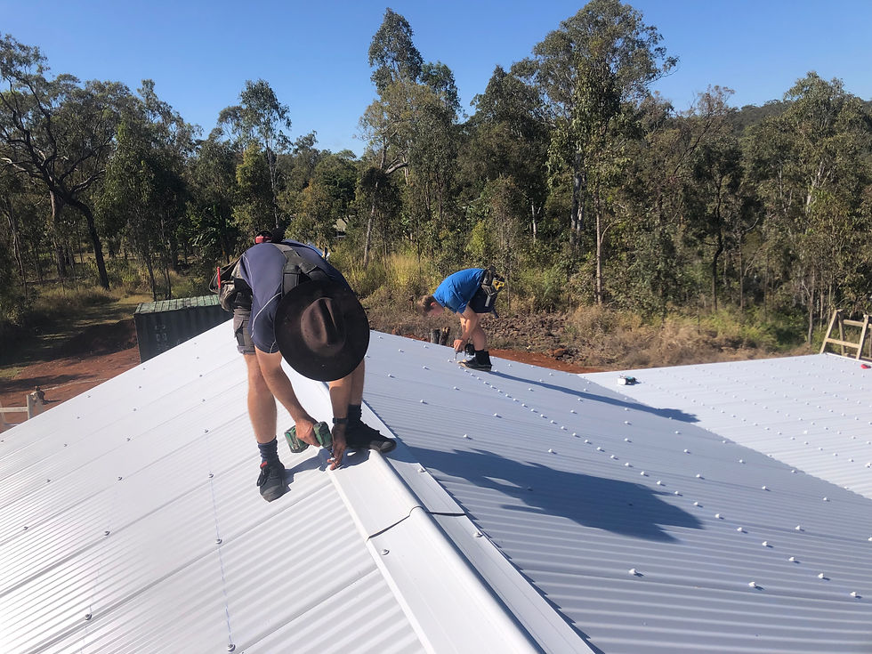 Two roofing carpenters installing a white colourbond roof