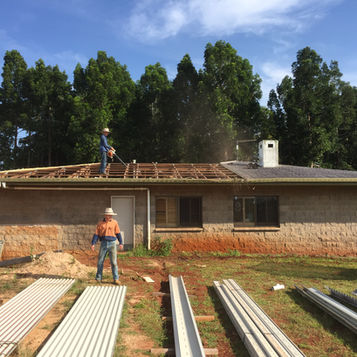 Two trades men working on a re-roof
one is on the ground looking at the sheets and another is cleaning the roof.