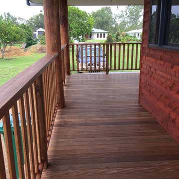 Weather board cladded house with a hardwood deck and handrails