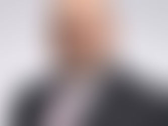 Jeremy Dobbe, an atttorney at Di Renzo & Bomier, in a suit smiles warmly against a plain gray background. He wears a pink striped tie, creating a formal and friendly mood.