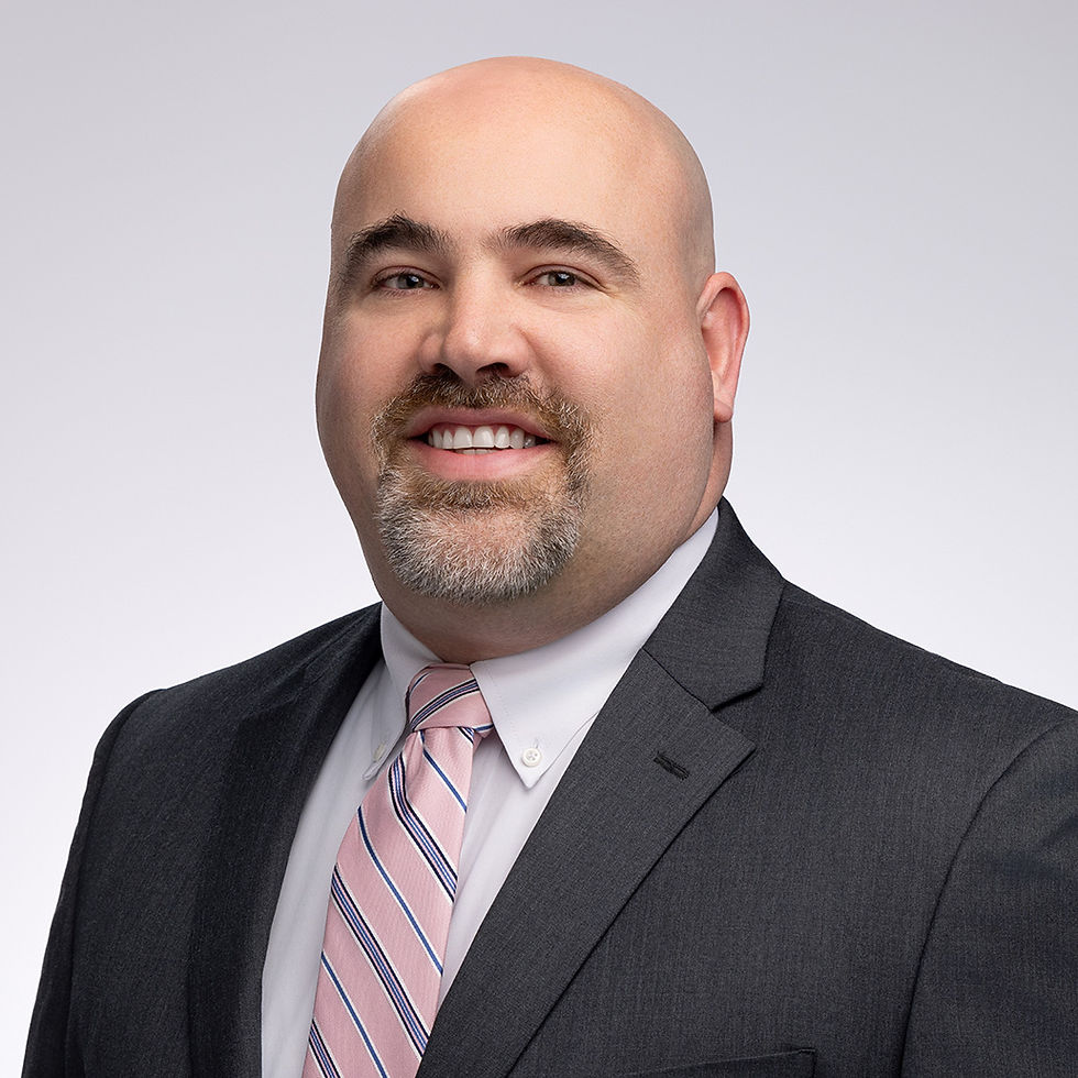 Jeremy Dobbe, an atttorney at Di Renzo & Bomier, in a suit smiles warmly against a plain gray background. He wears a pink striped tie, creating a formal and friendly mood.