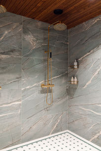 vihreänharmaat marmorilaatat kylpyhuoneessa, messinkiset yksityiskohdat ja rauhallinen spa-tunnelma