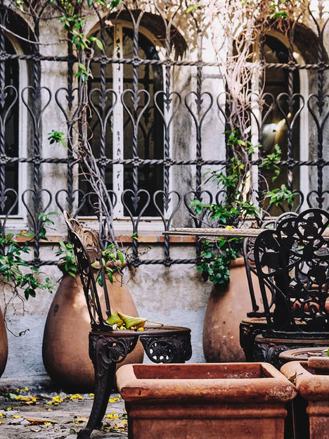 French patio with large pots, railing sand a coffee table