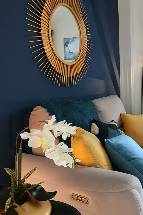 Elegant room with a gold mirror, blue wall, and decorative pillows