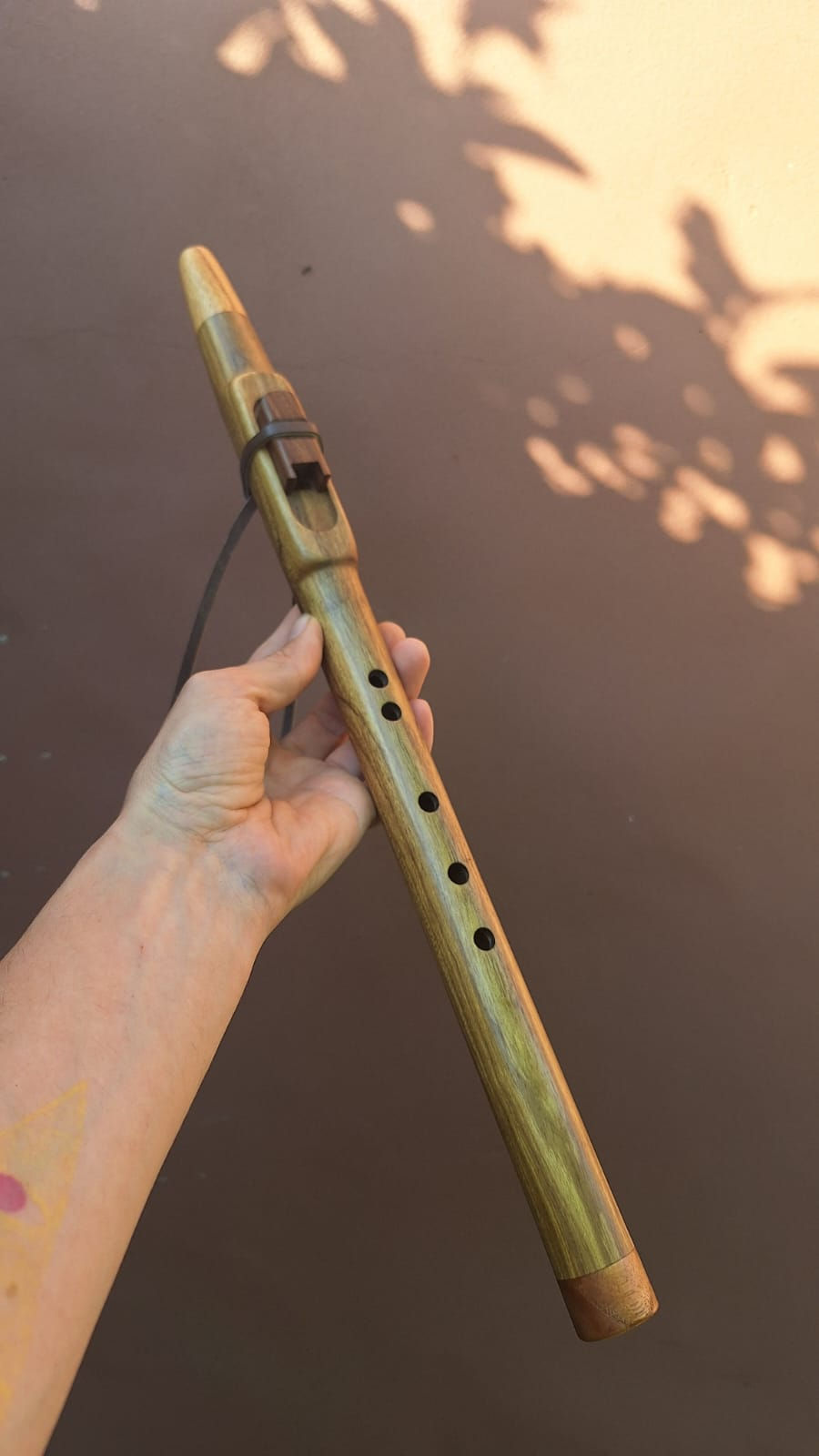 Mano sosteniendo una flauta nativa de madera