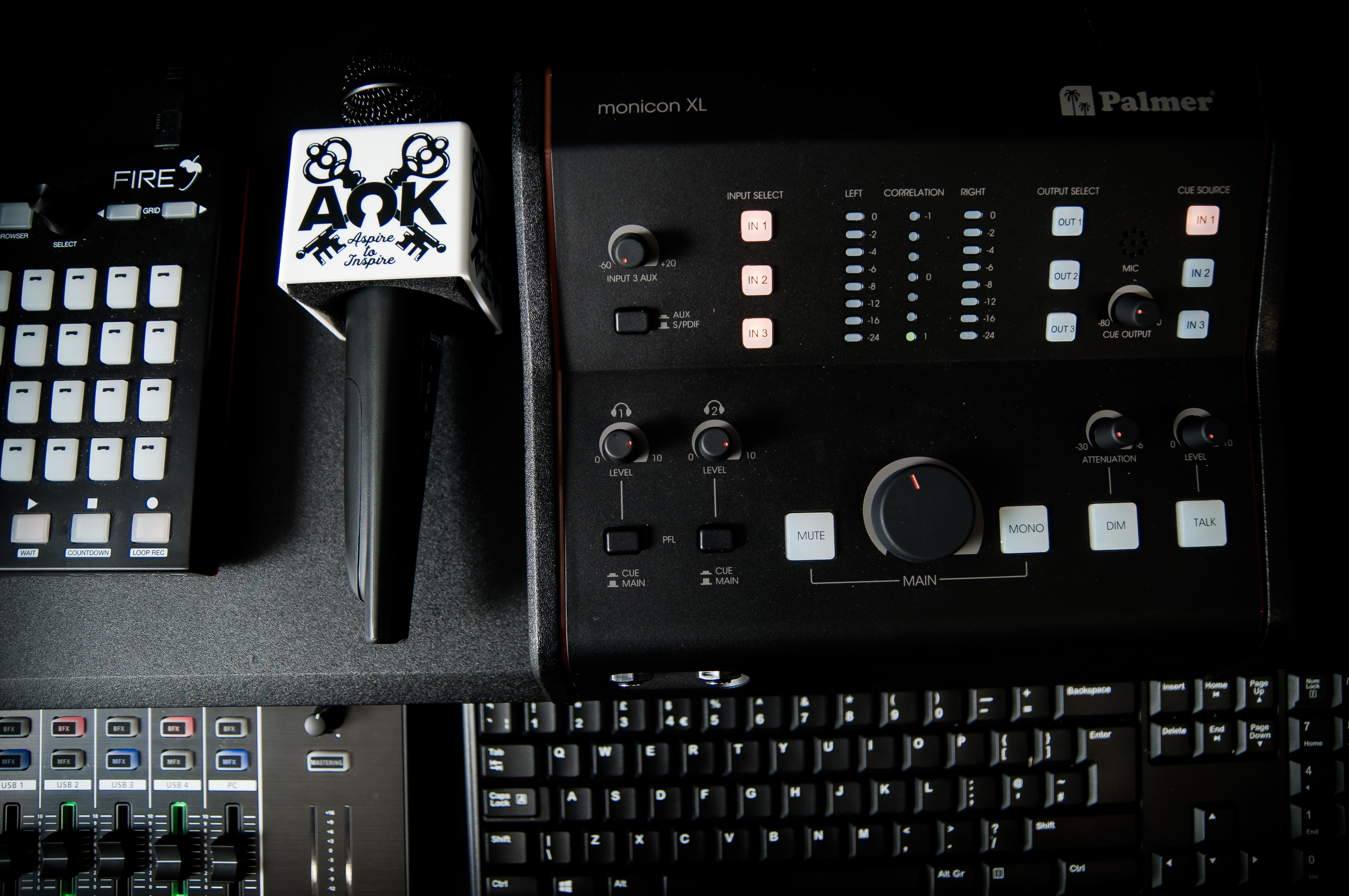 A.O.K Music Group's branded podcast microphone beside its audio mixer and recording controls.