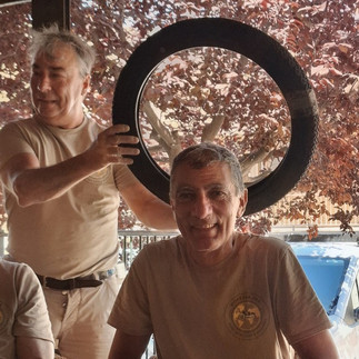 un homme qui tient un pneu au dessus de la tête d'un autre en guise d'auréole.