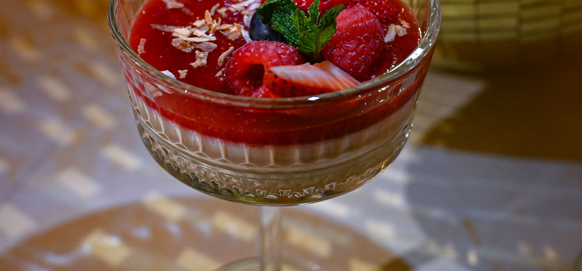 Vanilla and berries panna cotta in a coupe glass with disco ball backdrop