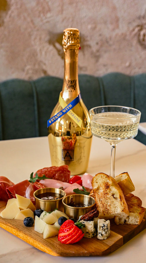 Cheese and meat board with a gold prosecco bottle marked Stand with Ukraine