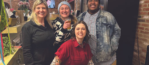 Four young adults smile together