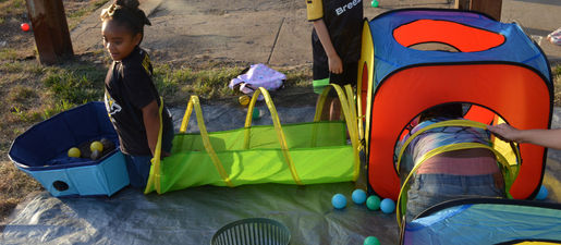 Kids play in a simulated sewer system made of colorful mesh tubes and cubes.