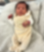A newborn baby lying on a blanket looking at the camera.