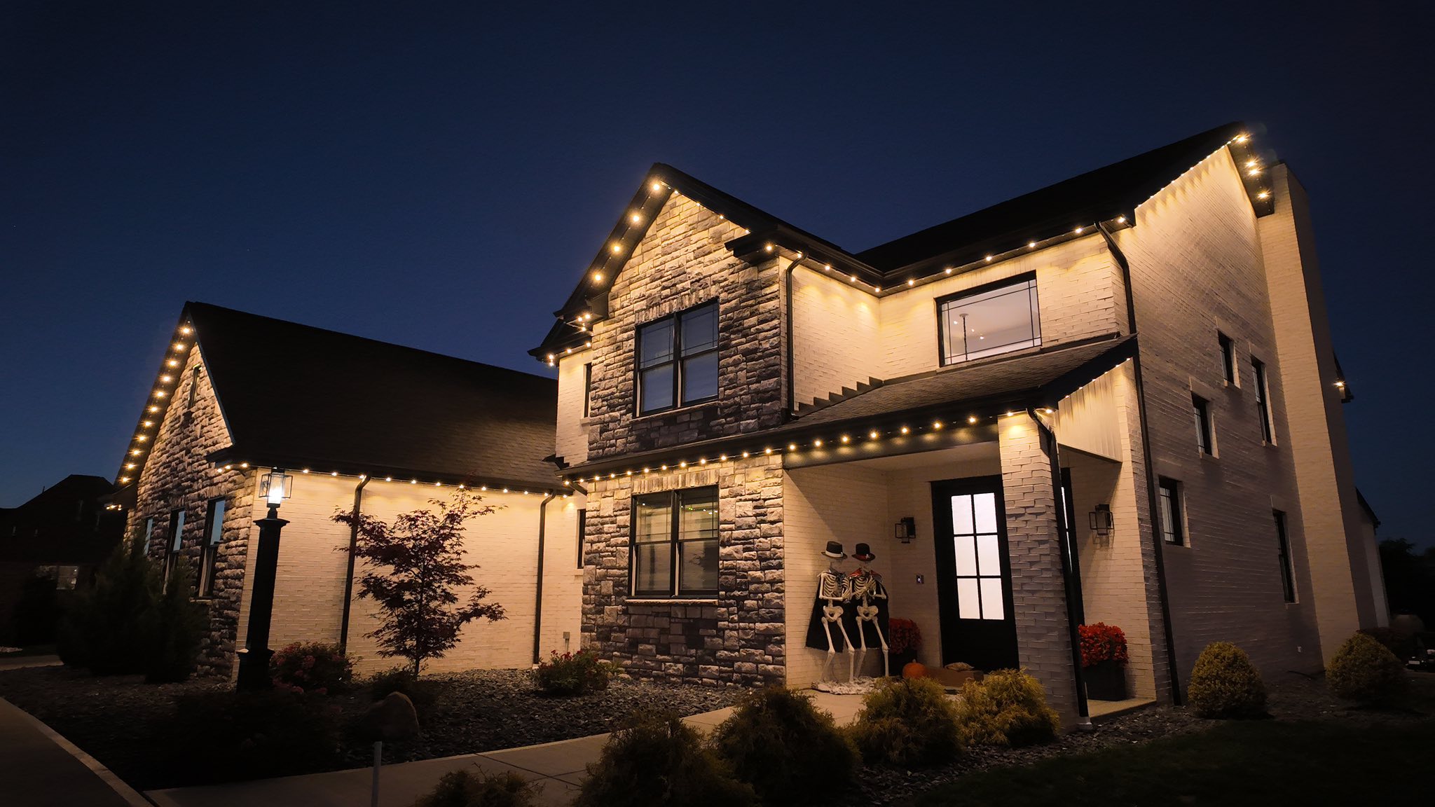 Stone-front home with warm permanent lighting