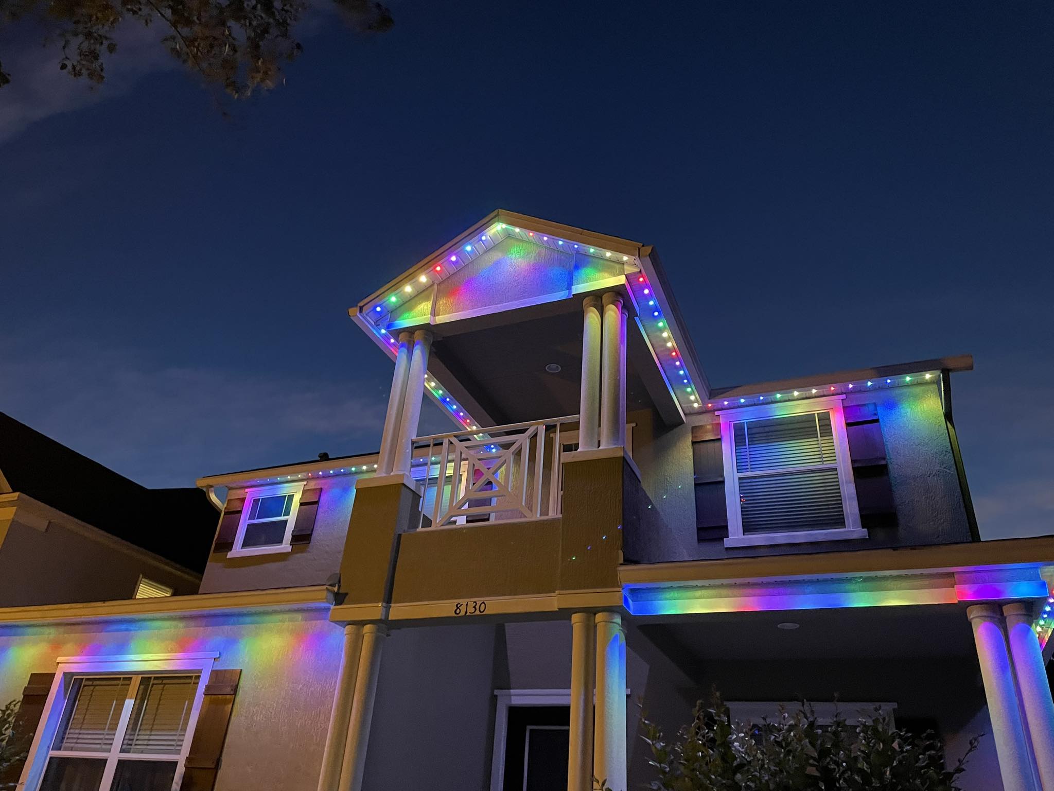 Two-story home with multicolor permanent lighting on the balcony