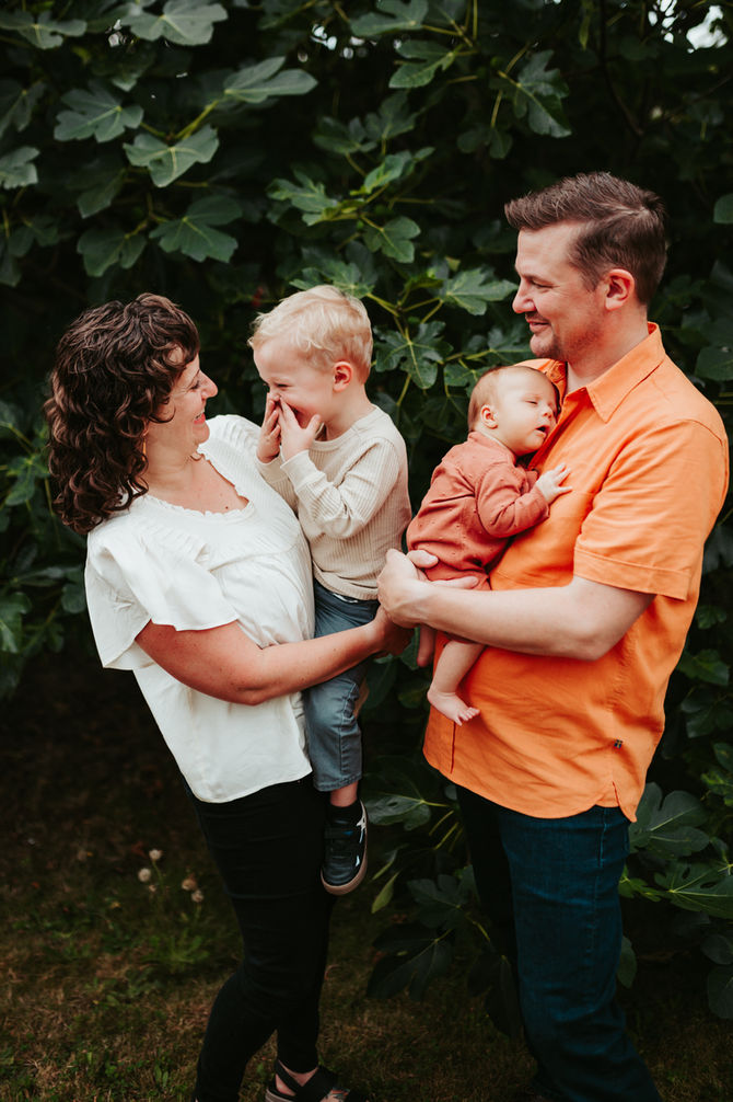 Mother and father hold toddler boy and infant girl