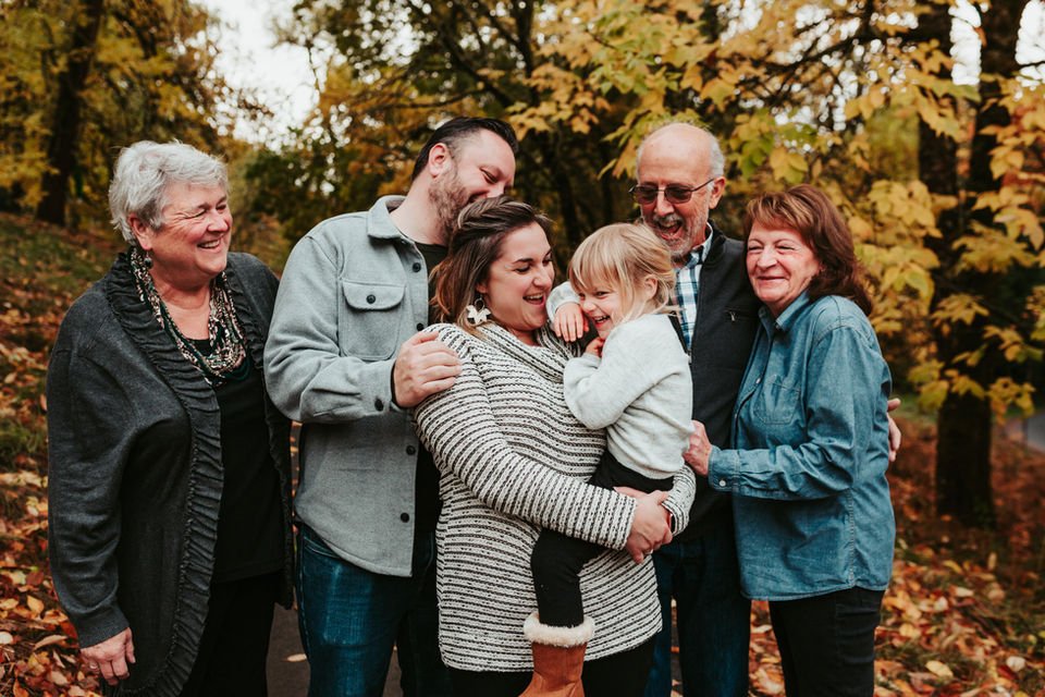 Little girl, parents, and grand parents stand together on fall day