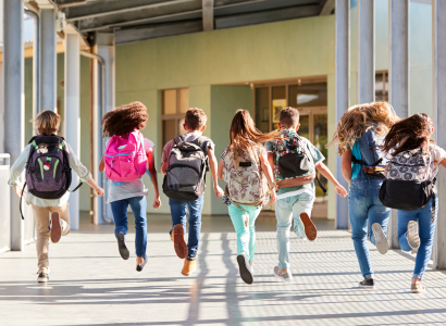 A group of students with their bag packs walking and jumping into the school.