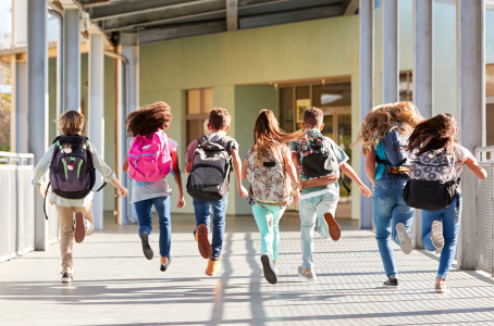 A group of students with their bag packs walking and jumping into the school.
