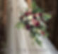 Deep green foliage with rich Burgundy roses and pheasant feather detailIn a luxury large bridal bouquet