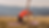 Woman in bright orange top doing a yoga stretch on a purple mat in a grassy field, with distant hills under a clear sky. Calm mood.