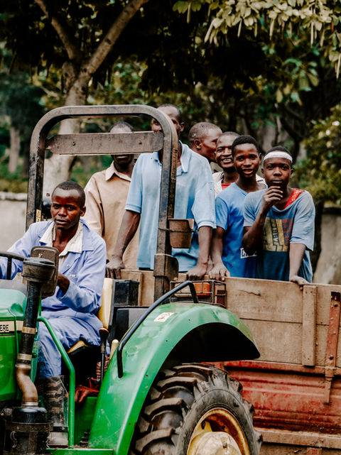 A green tractor carrying people form one side of the farm to the other. 