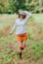 Brooke (The Tony Townie) wearing corduroy skirt and sweater runs through field of wildflowers.