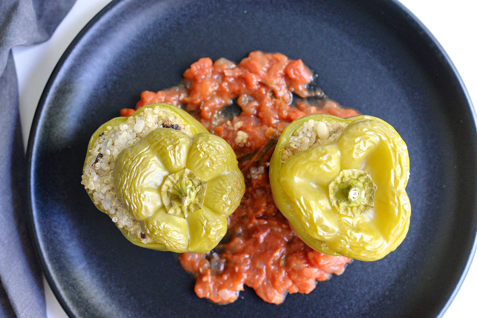 Poivrons farcis au quinoa et olives, recette vegan et sans gluten, servis avec une sauce tomate maison, parfaits pour l'été.