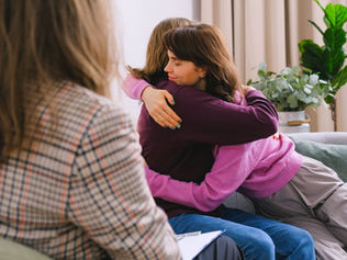 Two women hugging during a therapy section through family counseling