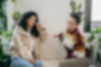 Two women smiling and talking indoors, representing sliding scale therapy support in Western Massachusetts