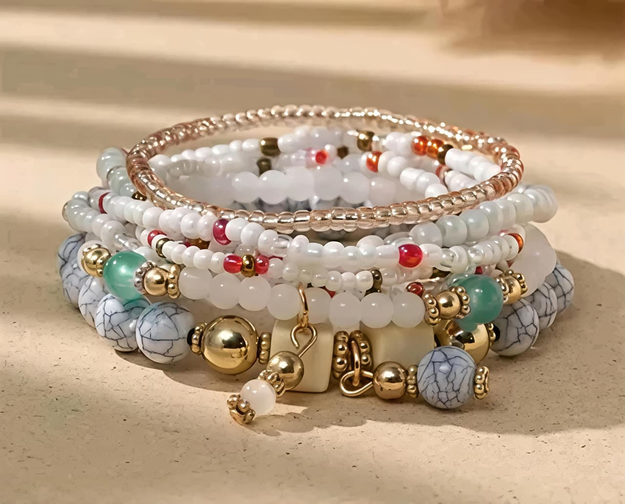 Layered beaded bracelets with white, gold, and marbled grey