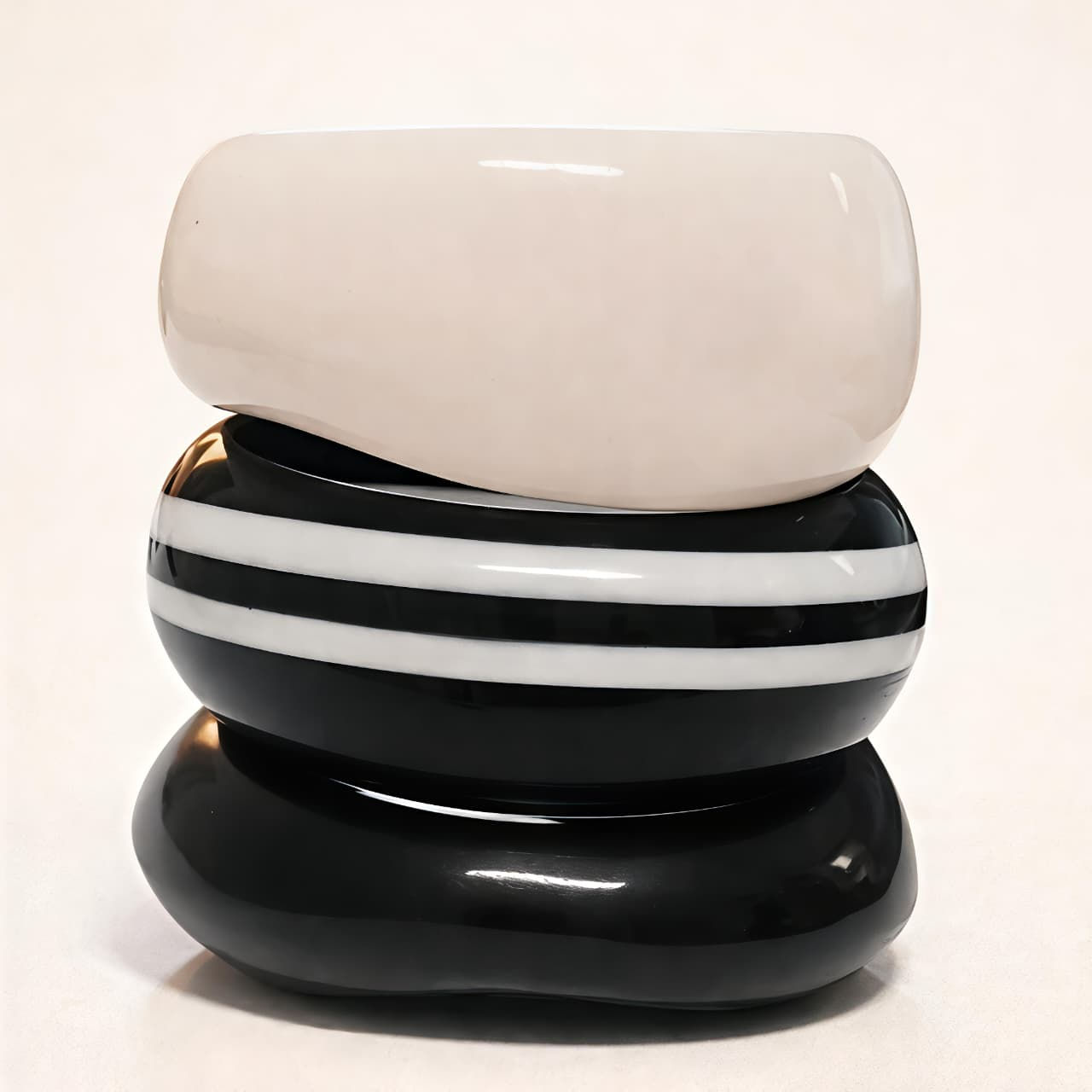 Three stacked bangles: white, black with white stripes, and black