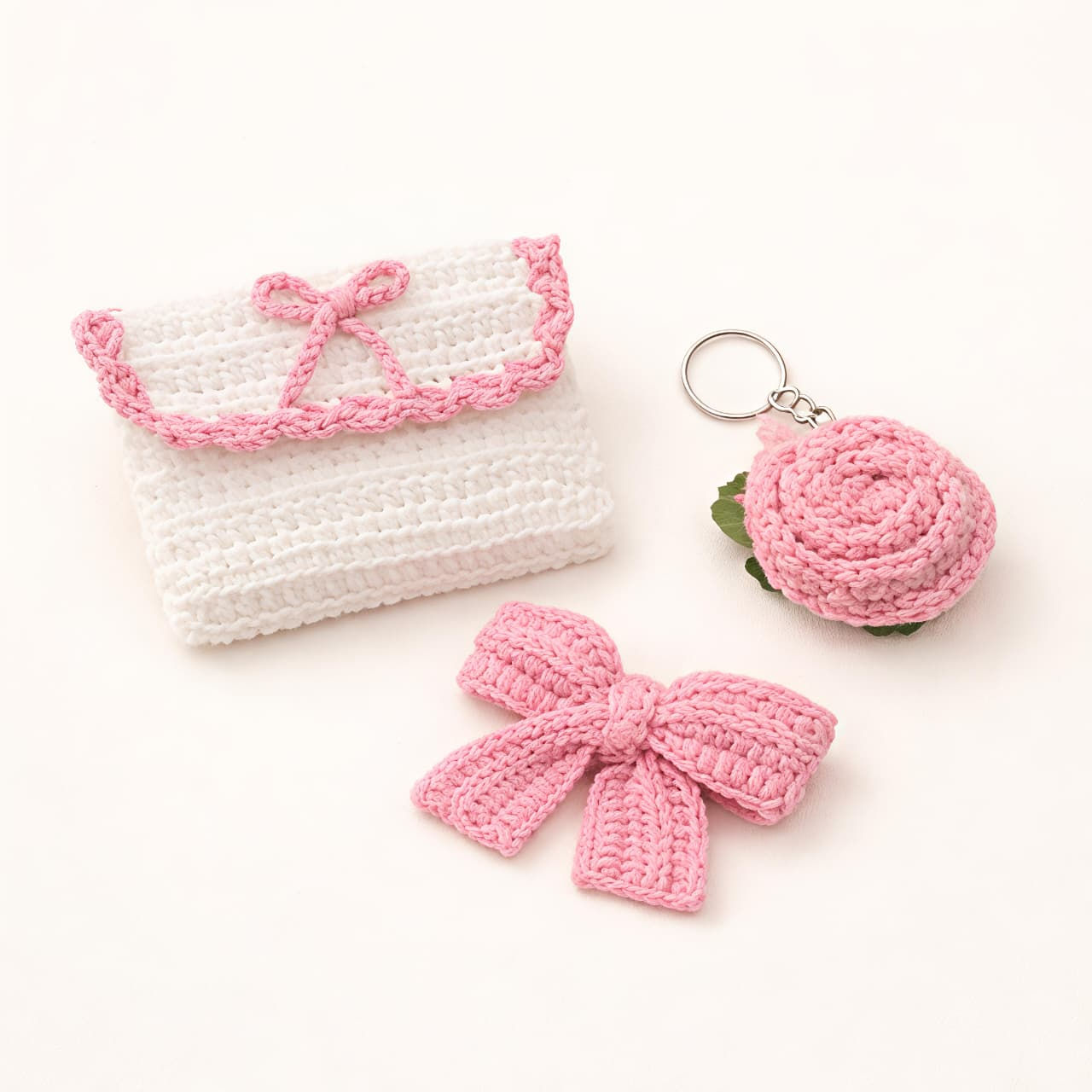 Crocheted white pouch, pink bow, and rose keychain