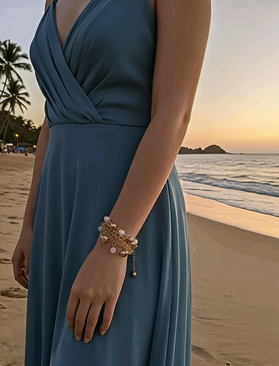 Woman in blue dress with pearl bracelet on beach at sunset