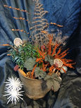 A recycled planter filled with live plants and dried decoration
