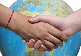 A hand shake infront of a globe