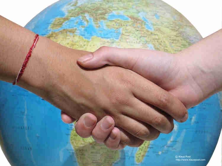 A picture of a globe with two shaking hands in front of it. 