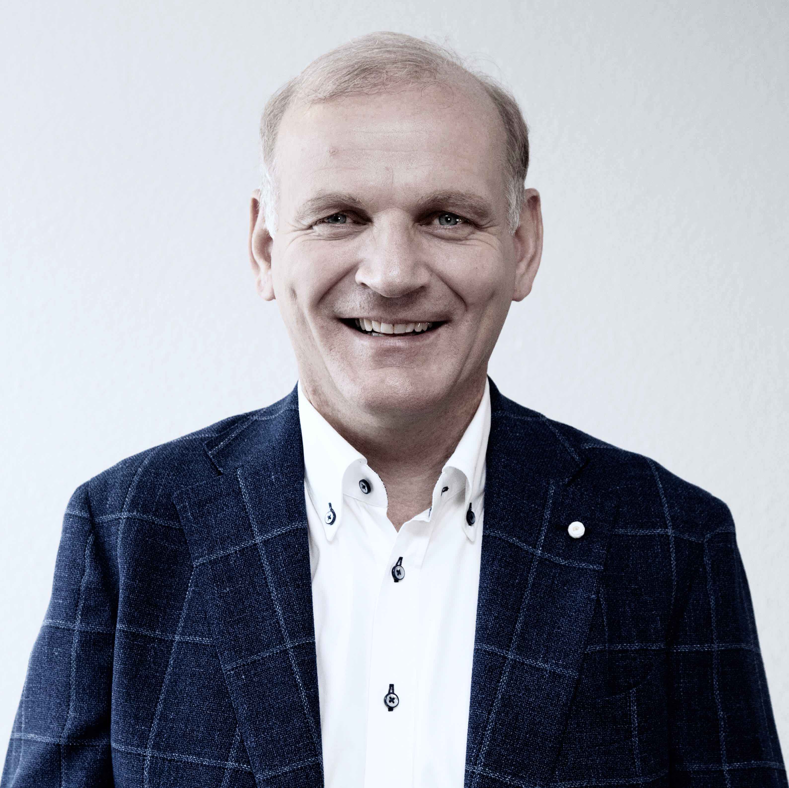Mann im Anzug lächelt, erzählt wie Gott ihm geholfen hhat