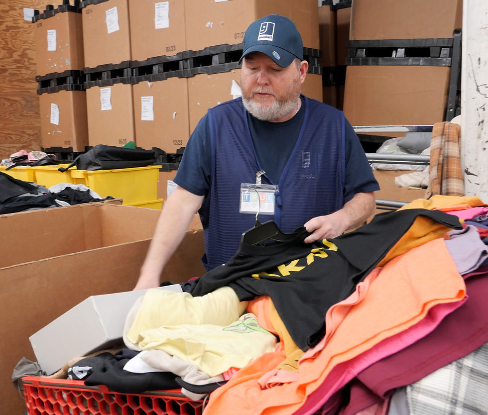 Dustin sorting clothes into bins while at work at Goodwill