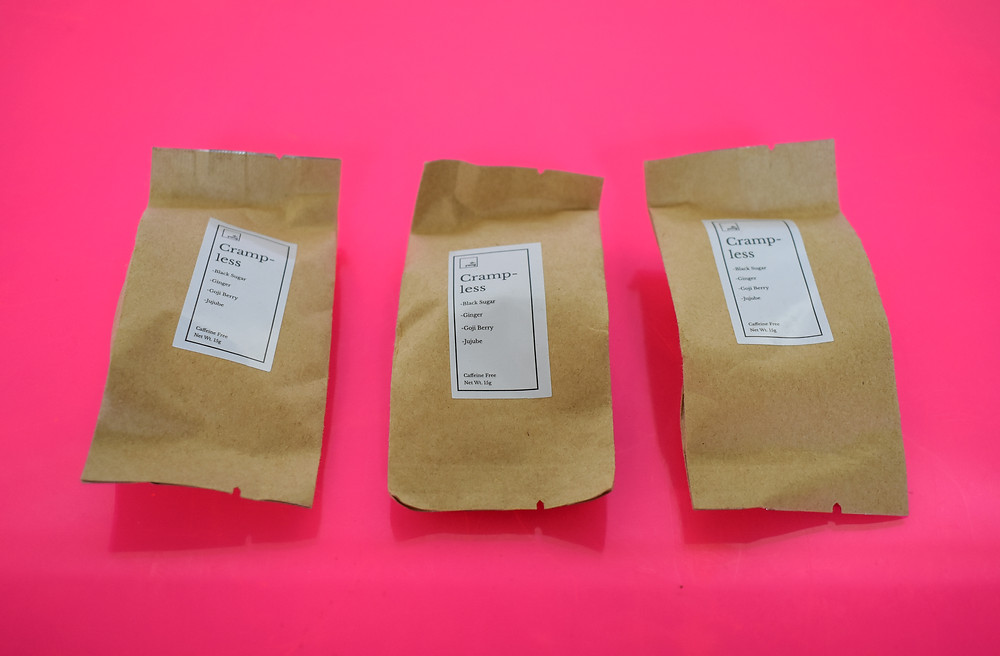 This is a photo of Dr. Yang Wellness tea in it's individual packaging on a pink background.