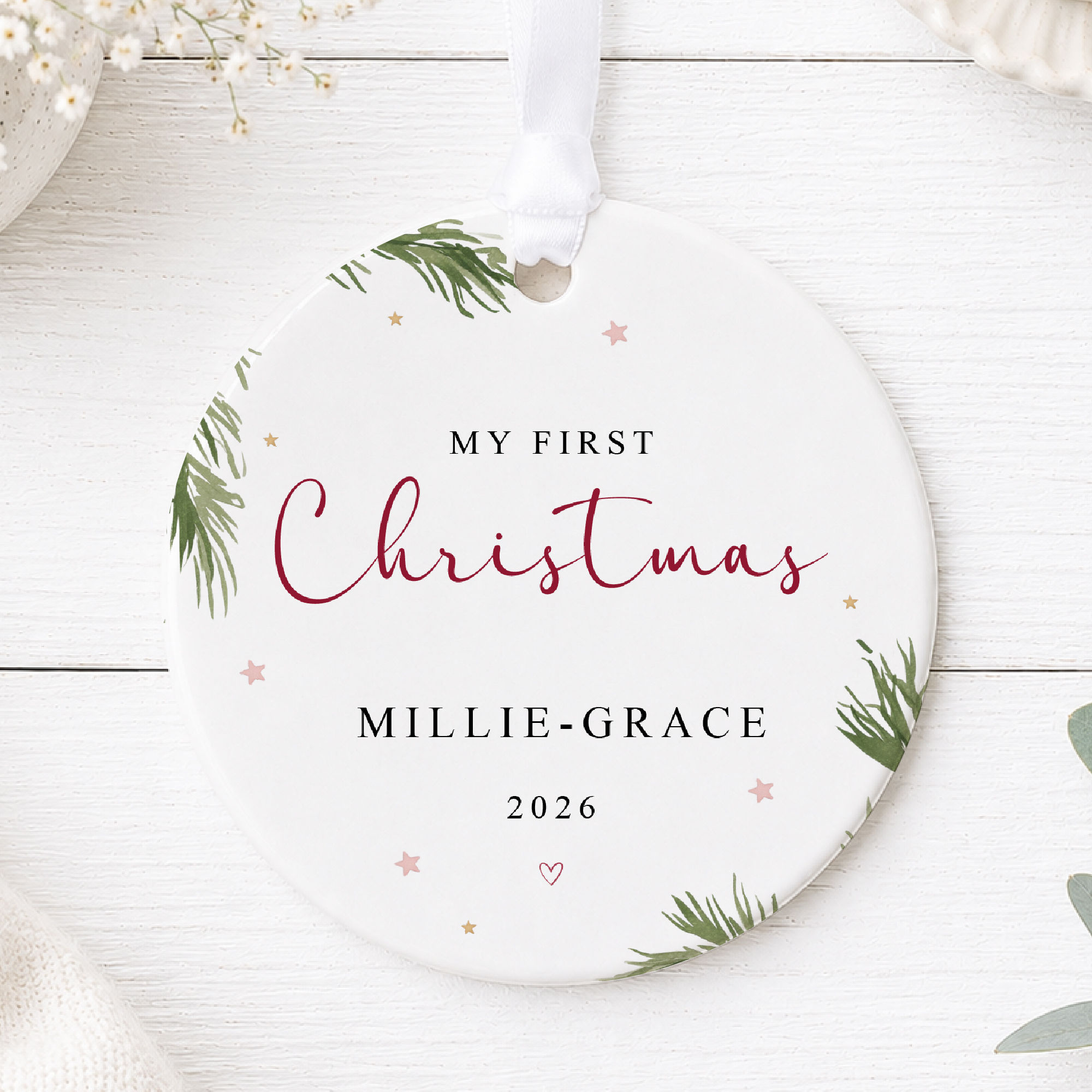 Personalised My First Christmas ceramic bauble for Millie-Grace, featuring burgundy script, pink stars and green pine branche